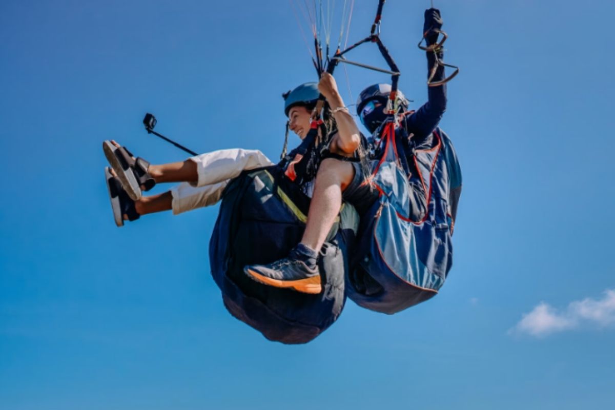 Paraglider flying above green volcanic slopes in Guatemala — adventure tour Antigua