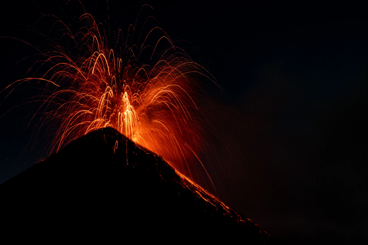 Fuego volcano erupting at night viewed from Acatenango base camp Guatemala — lava and ash lighting up the dark sky
