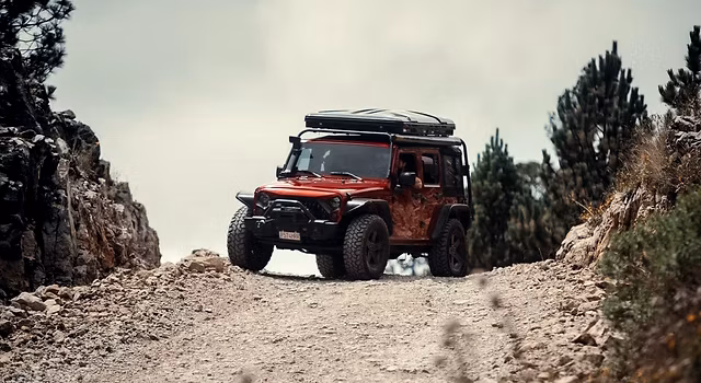 Un 4x4 sube por un camino de tierra hacia el volcán Acatenango al atardecer, con el volcán de Fuego en erupción al fondo, en Guatemala — excursión guiada en 4x4 desde Antigua con Cyman Travel