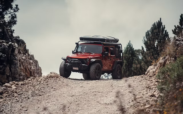 Un 4x4 sube por un camino de tierra hacia el volcán Acatenango al atardecer, con el volcán de Fuego en erupción al fondo, en Guatemala — excursión guiada en 4x4 desde Antigua con Cyman Travel