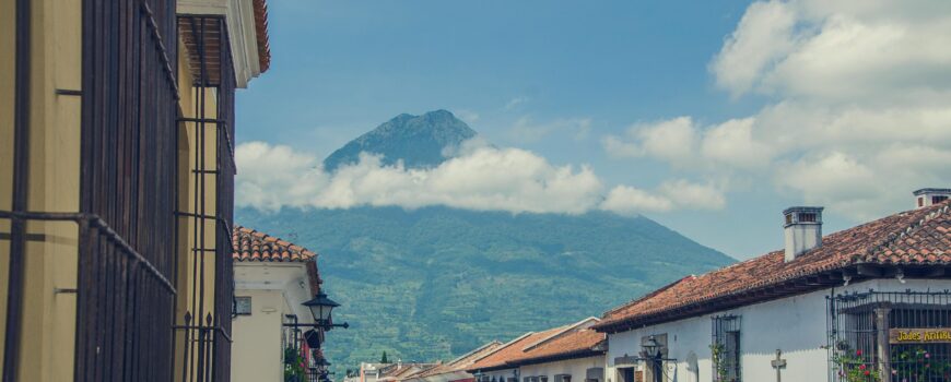 Aerial view of Antigua Guatemala colonial city surrounded by Agua Fuego and Acatenango volcanoes — city tour with Cyman Travel