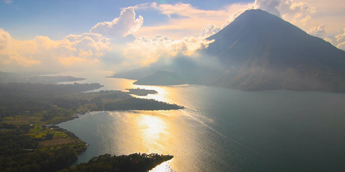 Wooden lancha boat crossing Lake Atitlán with Atitlán and Tolimán volcanoes in the background Guatemala