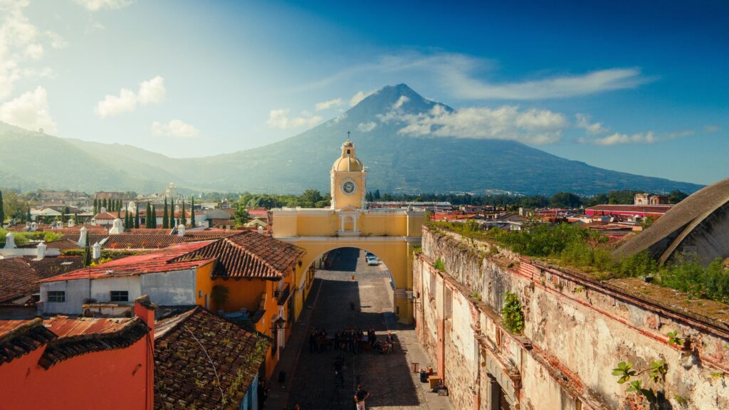 Las calles coloniales de Antigua Guatemala brillan tras la lluvia de una tarde de julio, con el arco de Santa Catalina al fondo