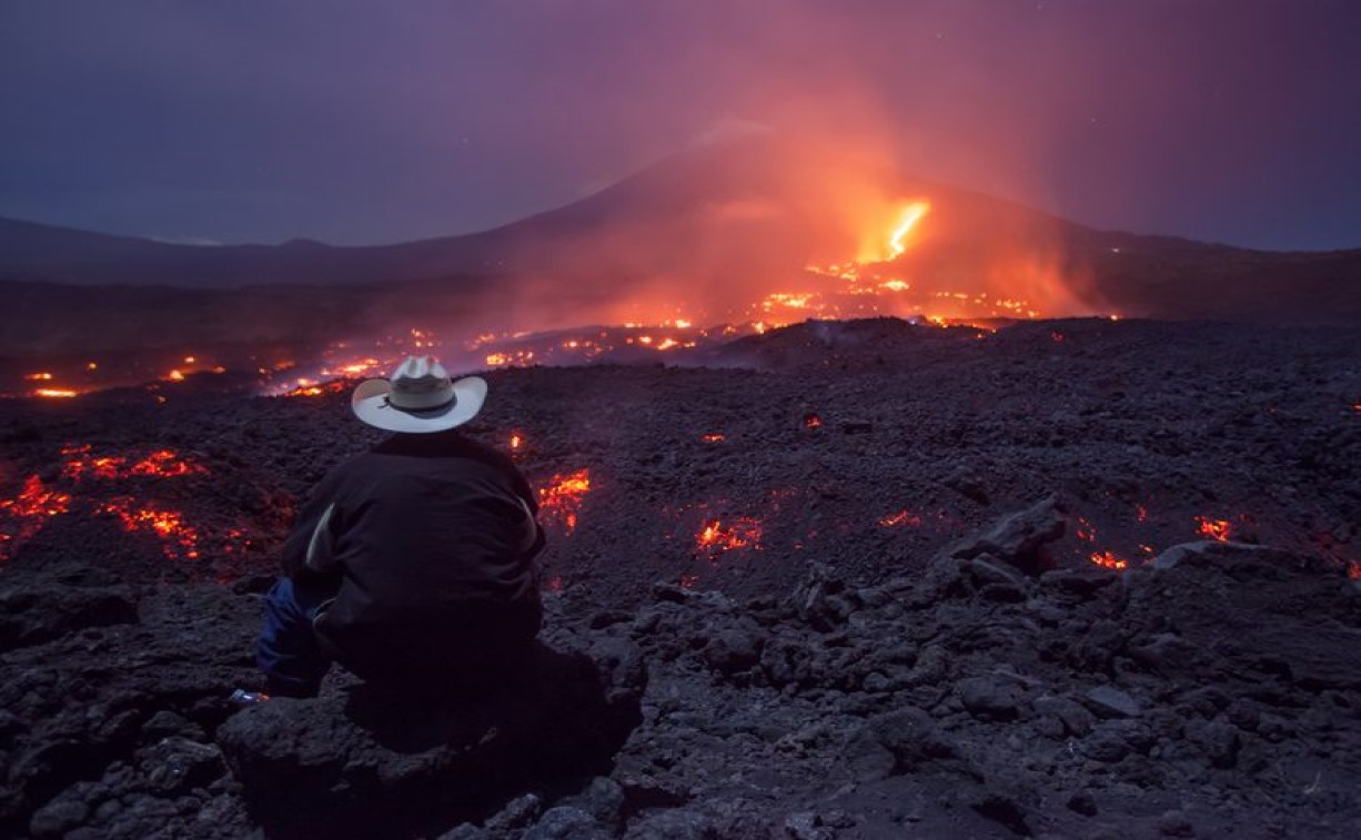 Hiker watching Pacaya Volcano lava flow at night near Antigua Guatemala