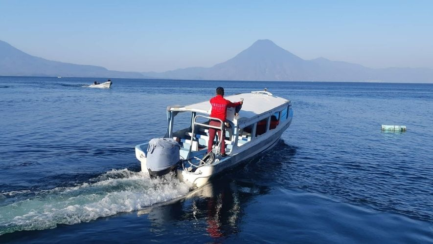 Una lancha de madera cruzando el lago Atitlán, en Guatemala, al amanecer, con el volcán San Pedro al fondo