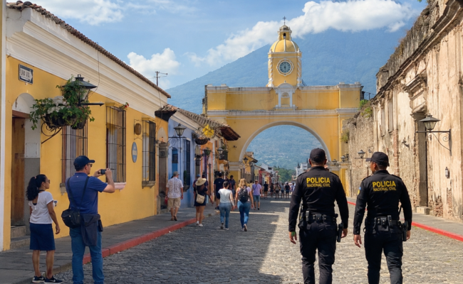 Tourists walking safely on cobblestone streets of Antigua Guatemala with police presence